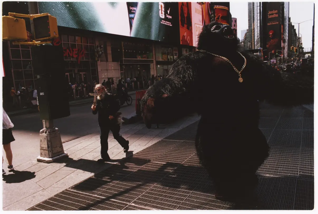 Times Square: Street performer in a gorilla costume stands in Times Square, New York City, surrounded by pedestrians, billboards and city traffic.