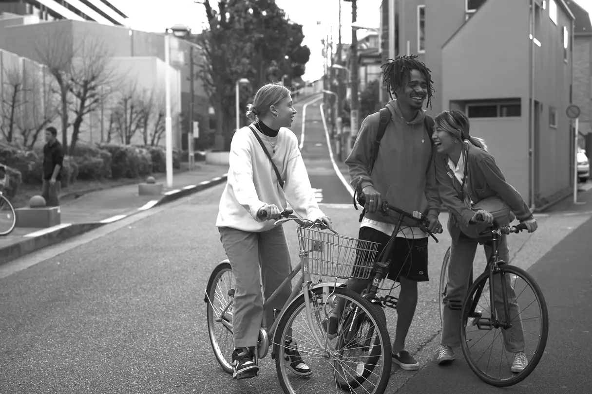 Cyclists in a city street — Black-and-white photograph of three friends smiling and talking while standing with bicycles on a quiet urban street.