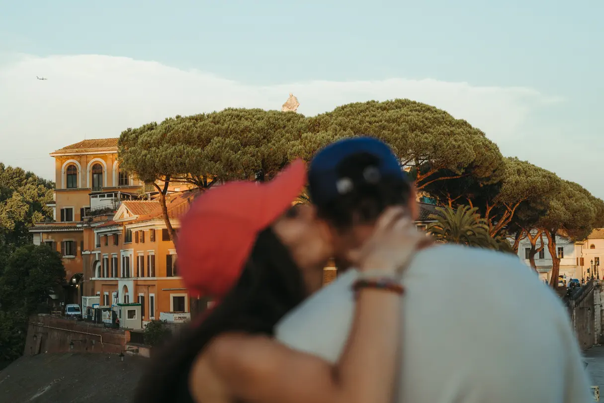 Couple kissing in Rome — Couple kissing in the foreground with historic Roman architecture and umbrella pine trees softly focused in the background.