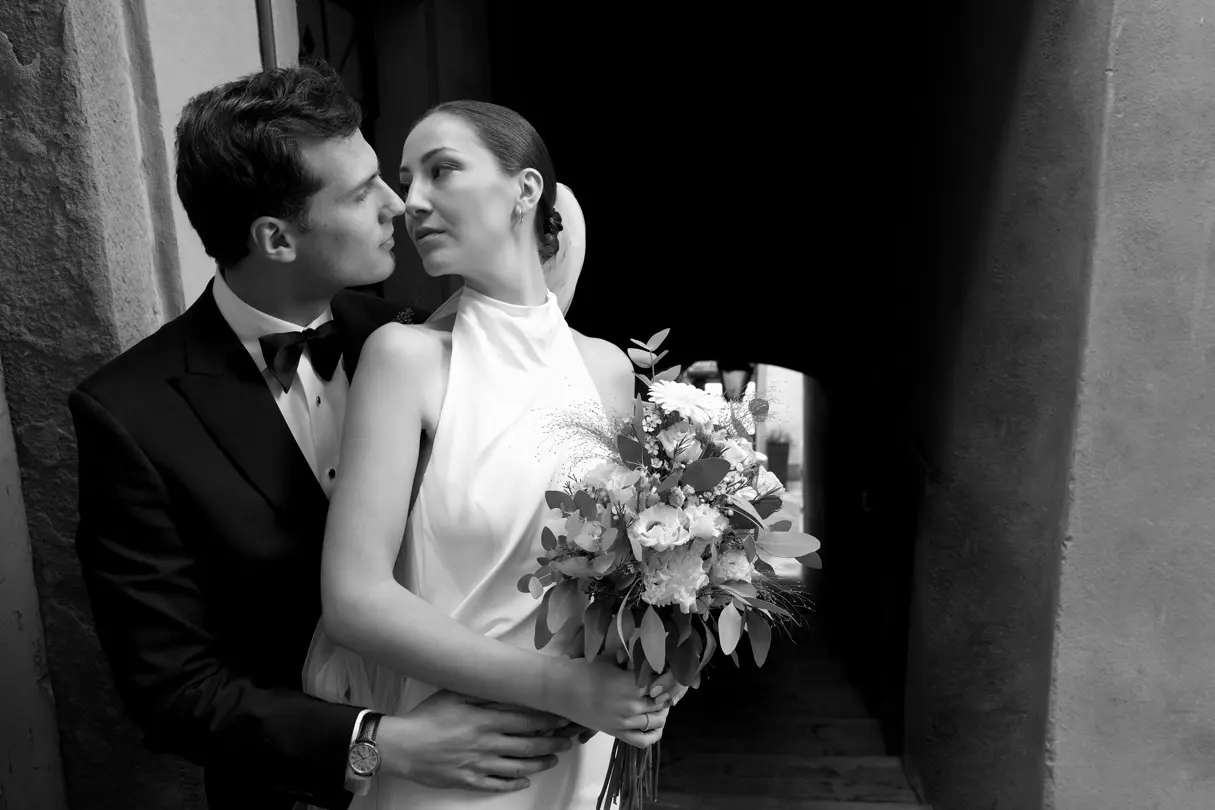 Black-and-white wedding portrait — Bride holding a bouquet while standing with the groom in an intimate black-and-white wedding portrait.