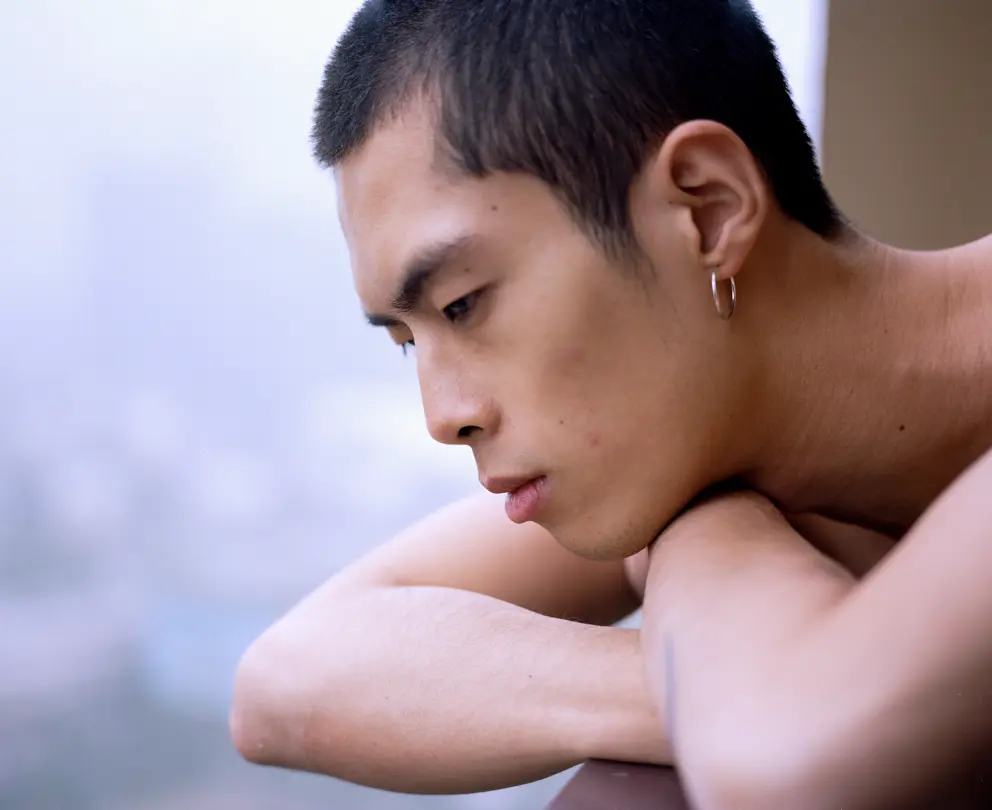 LOBA Newcomer 2023 image: Close-up portrait of a person resting their head on folded arms.