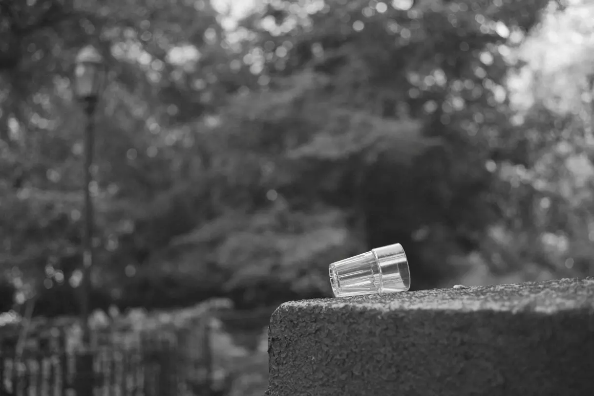 A glass resting on a stone wall. `