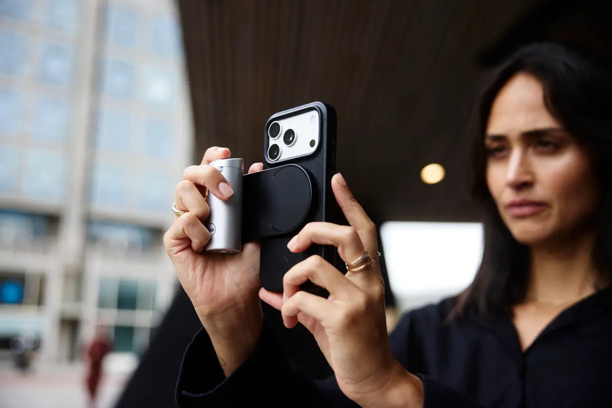 Woman using a smartphone with a Leica LUX grip in an urban setting