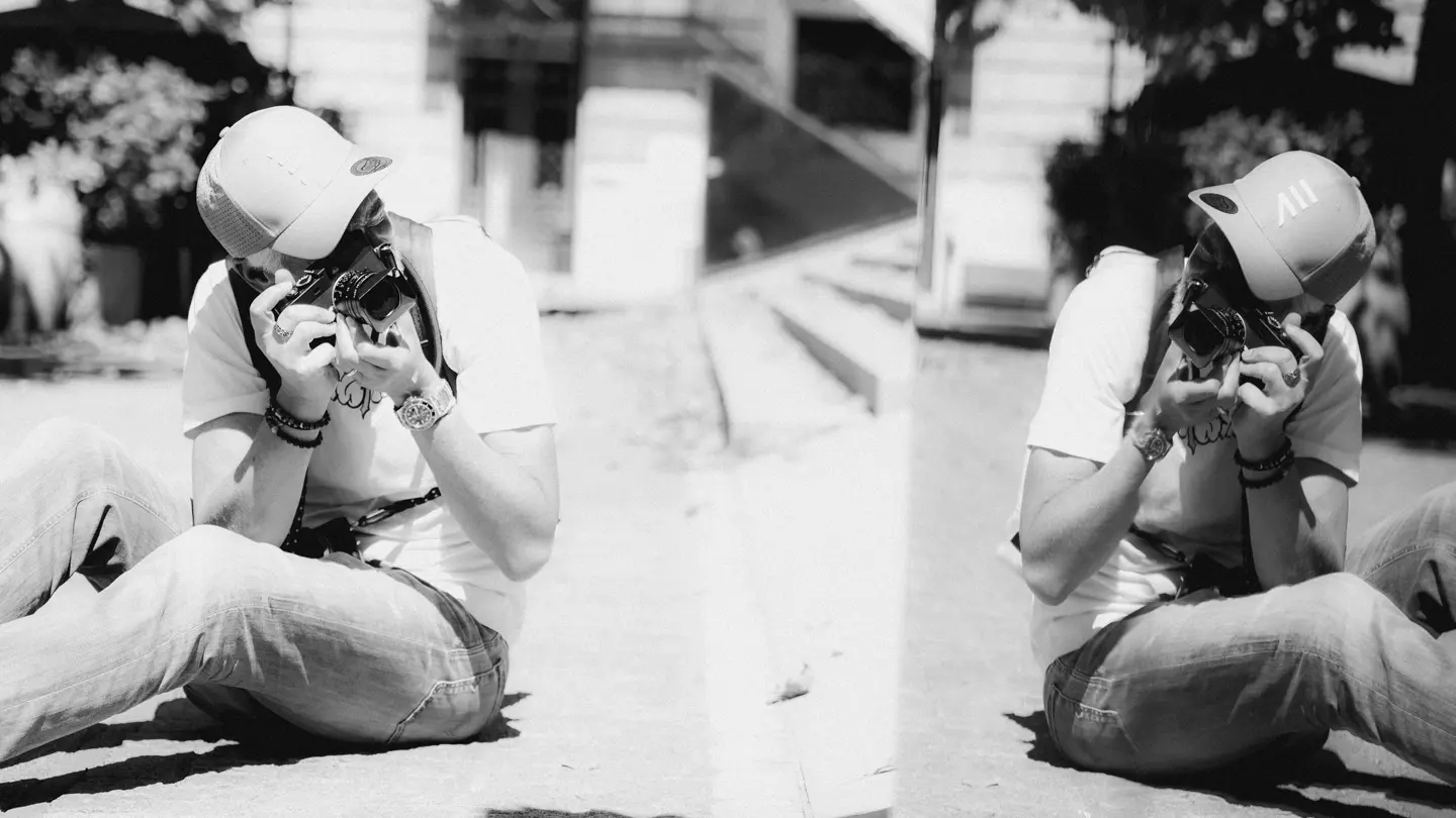 A black-and-white diptych showing a photographer seated on the ground, capturing images with a camera from a low angle.