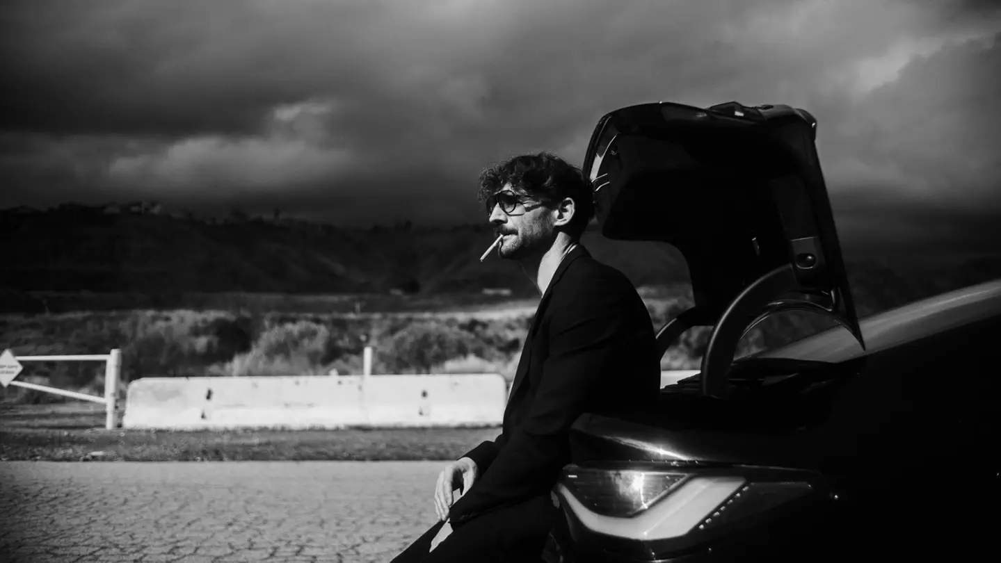 A person is leaning against a car