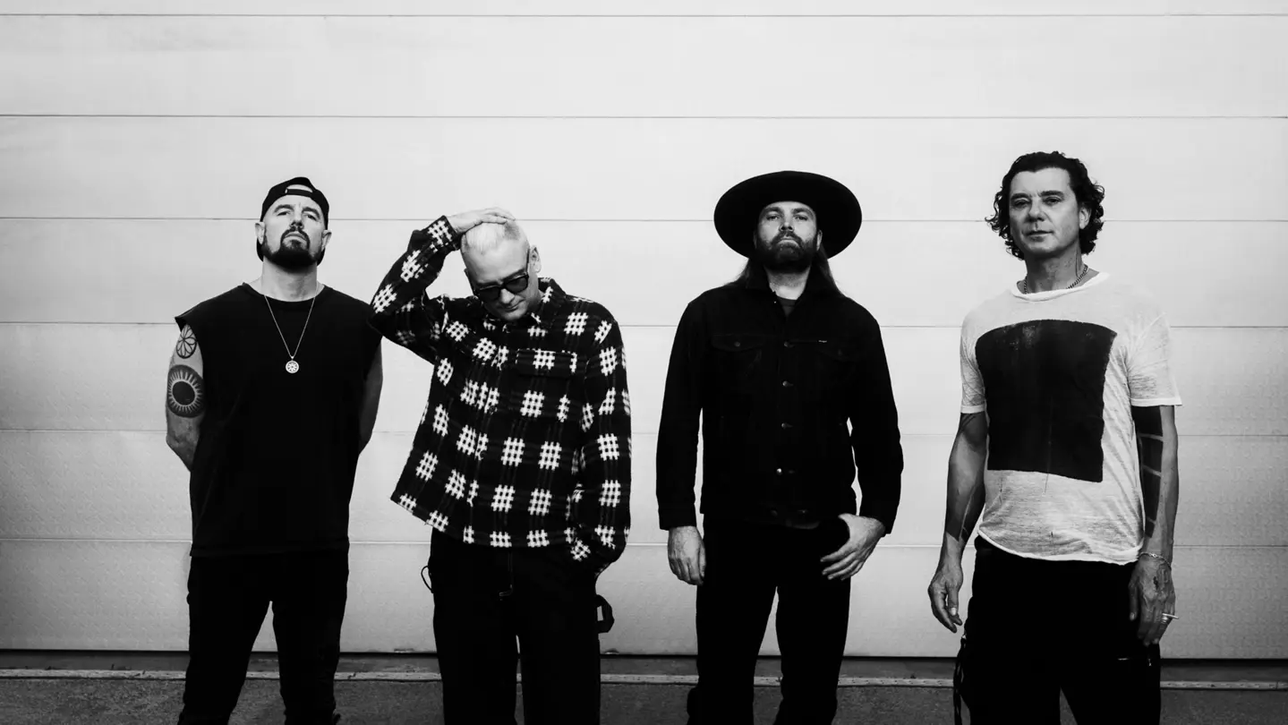 Four people are standing in front of a wall