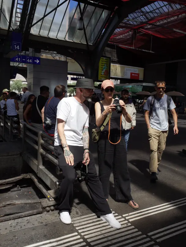 Photographers explore their cameras at a busy train station.