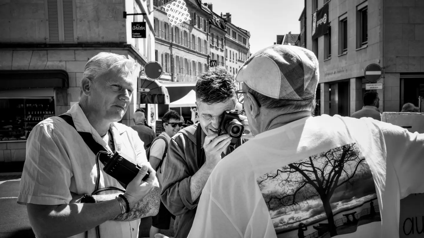 Three photographers interact during a street photography session.
