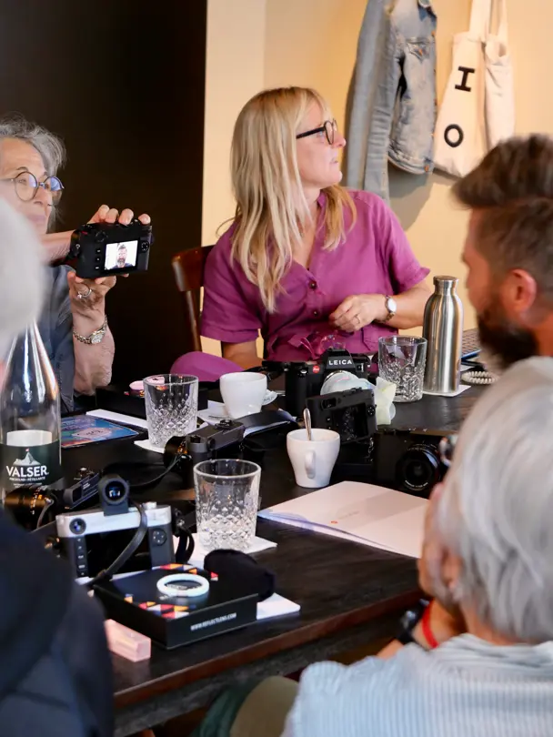Photography enthusiasts explore Leica cameras during an indoor workshop.