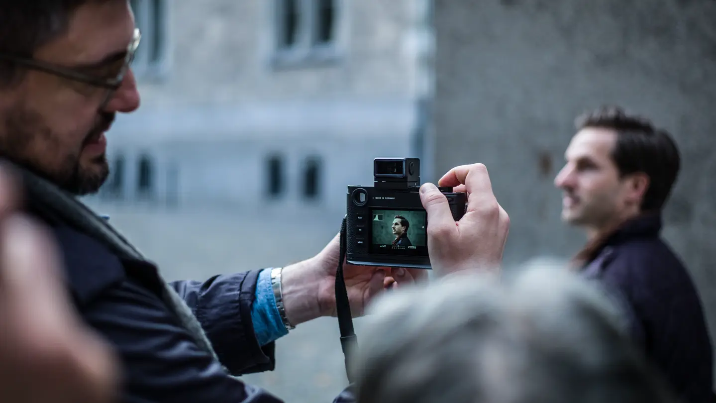 A photographer captures a portrait with a Leica camera during an outdoor photography workshop.