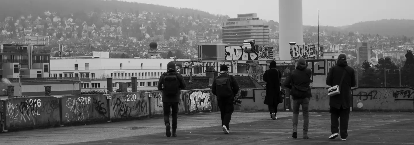 Five photographers explore a graffiti-covered rooftop overlooking the city during a photography walk.