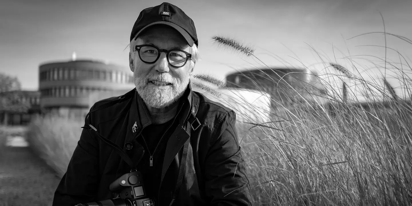 Portrait of photographer Ragnar Axelsson holding a Leica camera