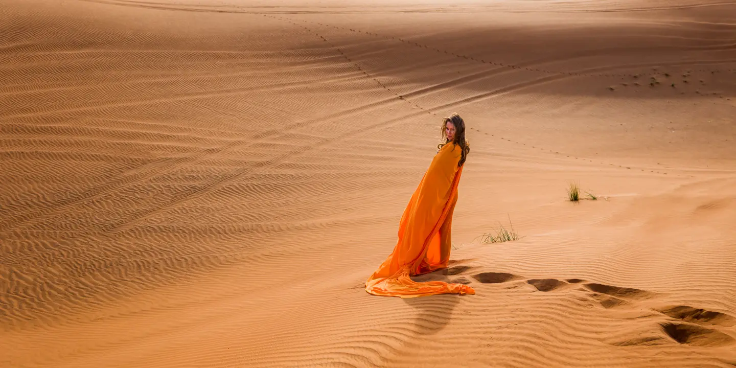 Woman in an orange dress standing in the desert.