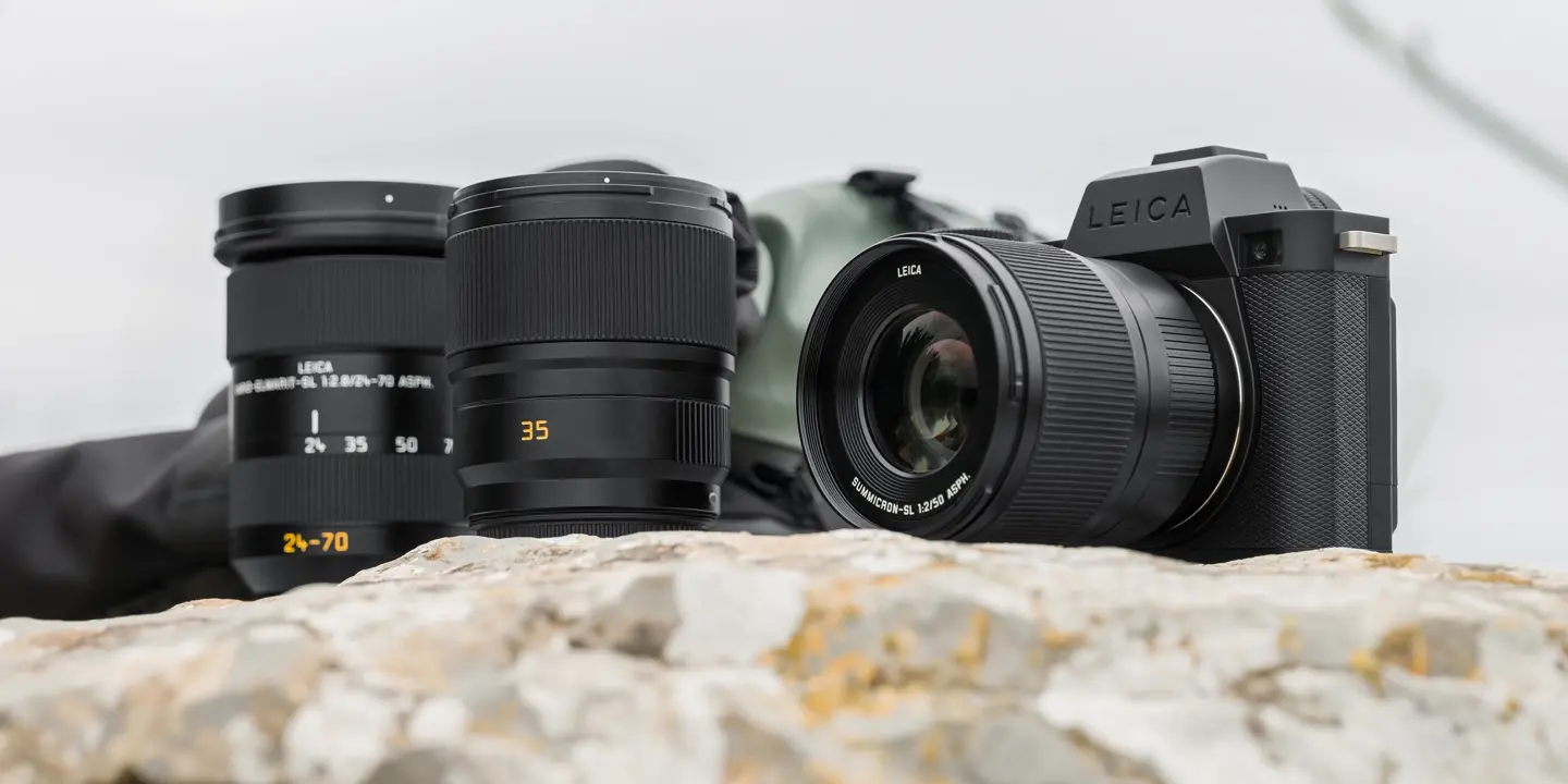 Leica cameras placed on a light-colored rock or stone with the sky in the background