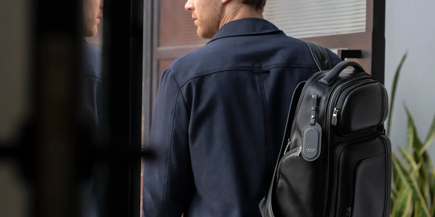 Man wearing a suit with a rucksack and a Leica leather tag