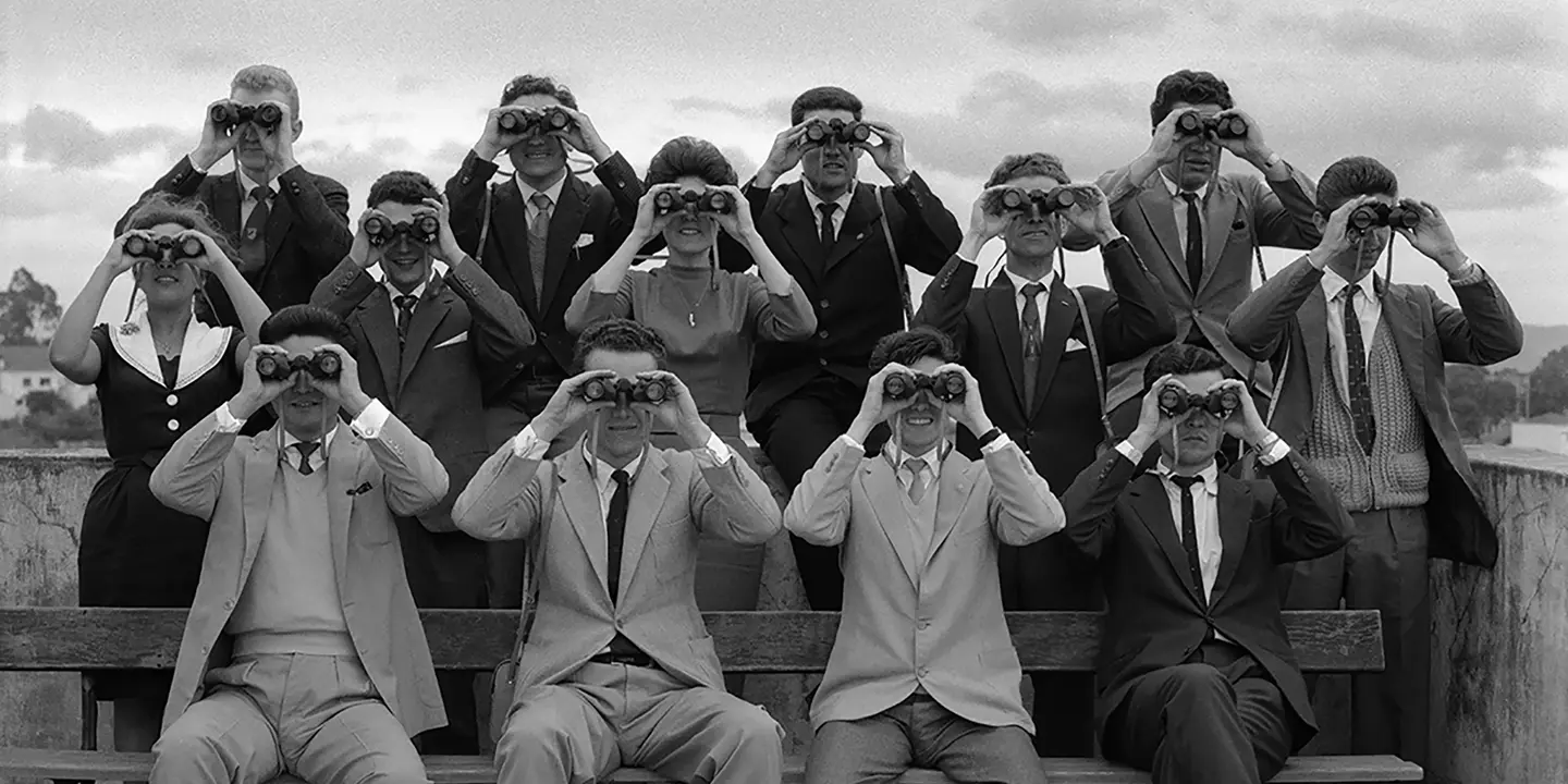 Women and men in 1960 with binoculars in front of their faces