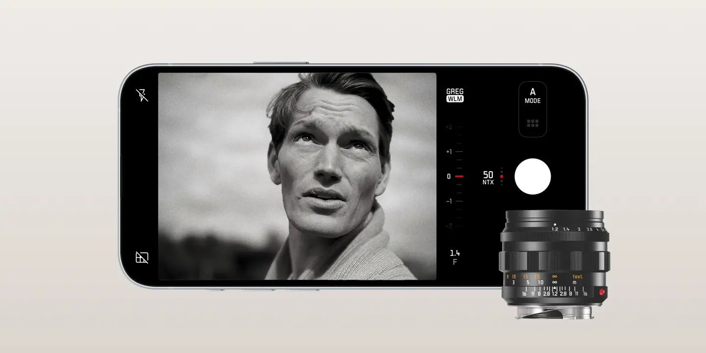 An iPhone displays an image with a man. In front of the phone is a Leica lense.