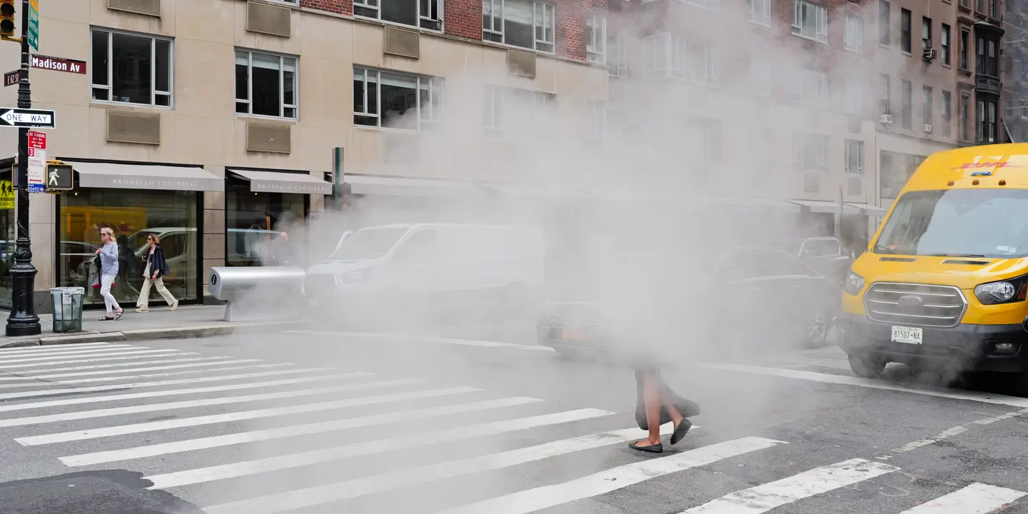 A woman walks along a pavement through the fog