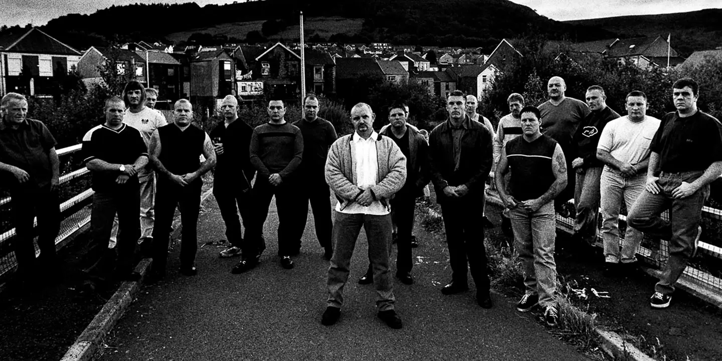 Black and white photo of a group of men posing in front of houses