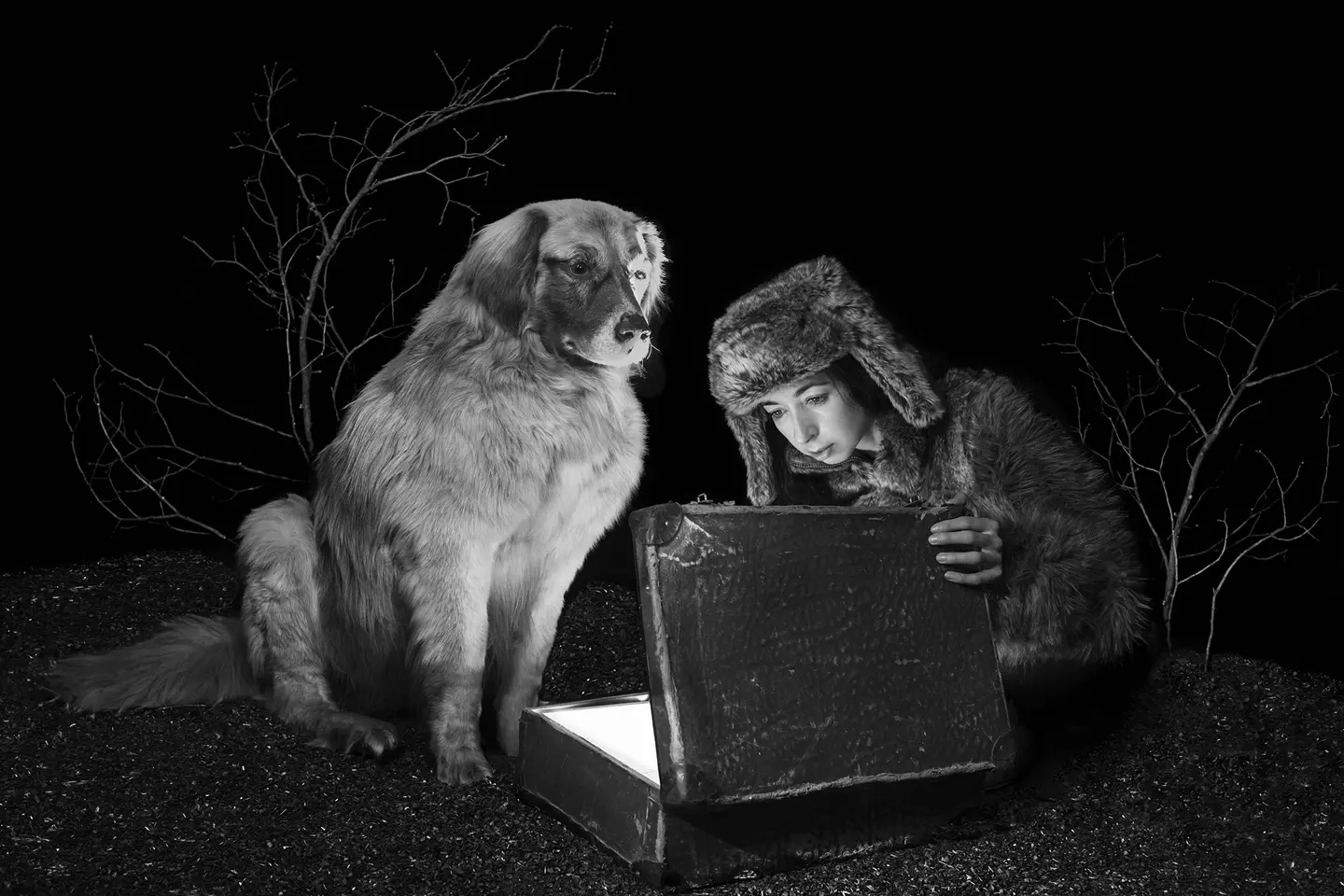 Viktoria Sorochinski and a dog looking into an old suitcase that is glowing inside.