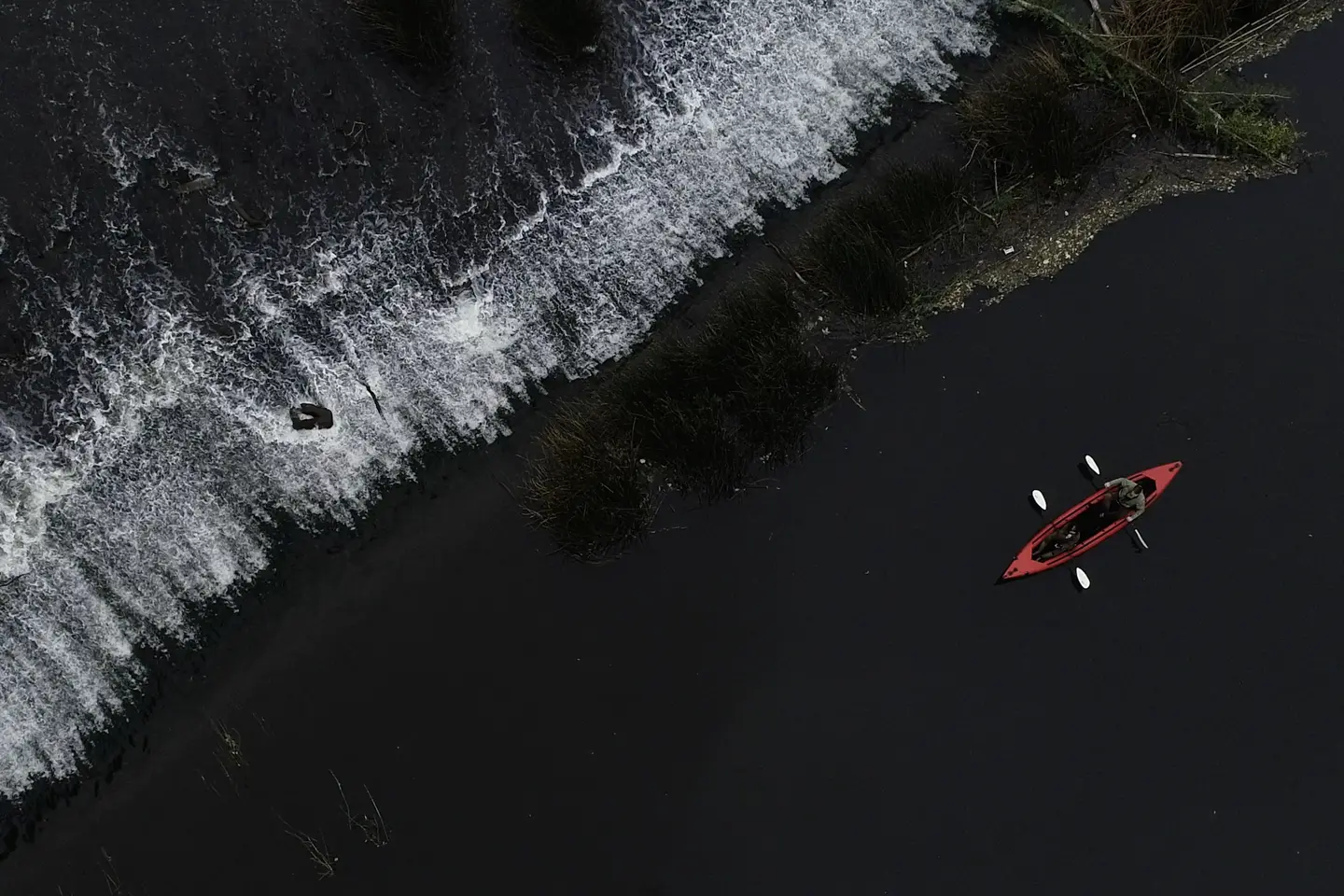 Red canoe paddling along the black sea coast.