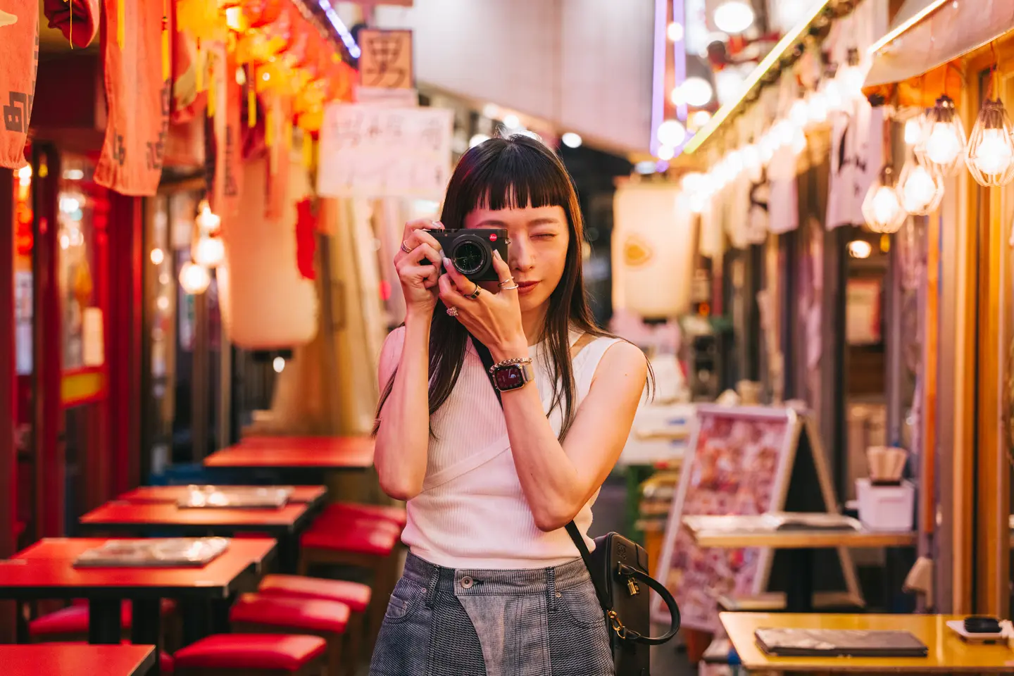 A woman takes pictures with a camera in a colorful, illuminated street.