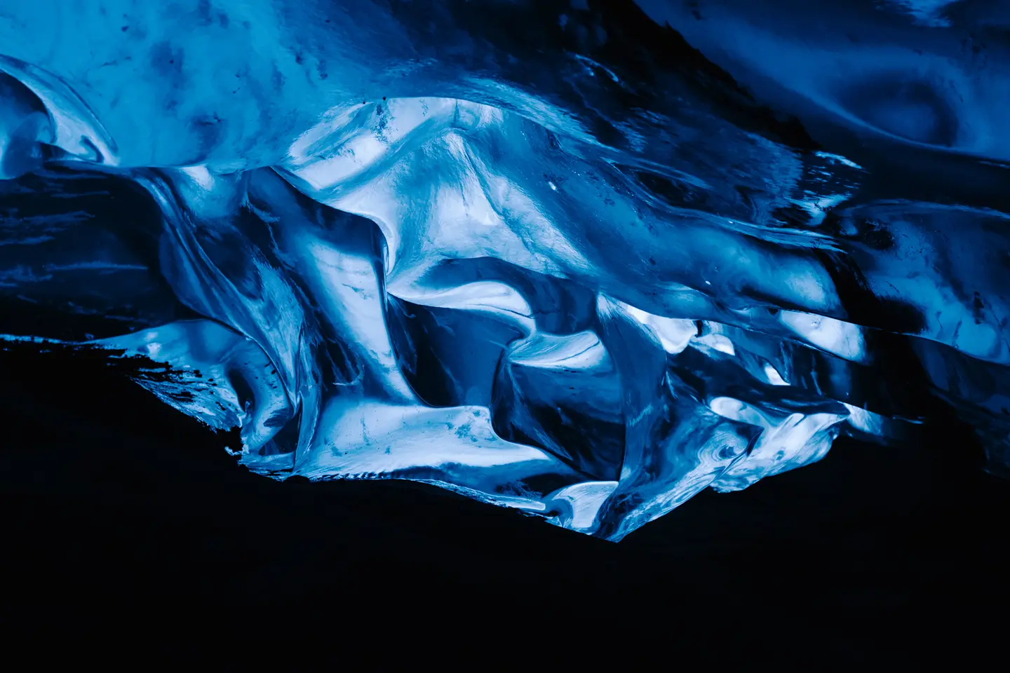 A glowing blue ice formation in a dark cave.