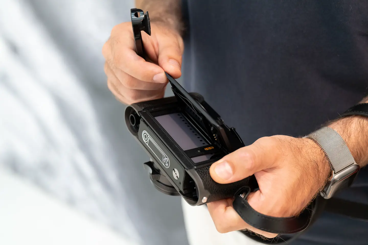 Close-up of the hands opening the back of the camera, where the camera roll is placed.
