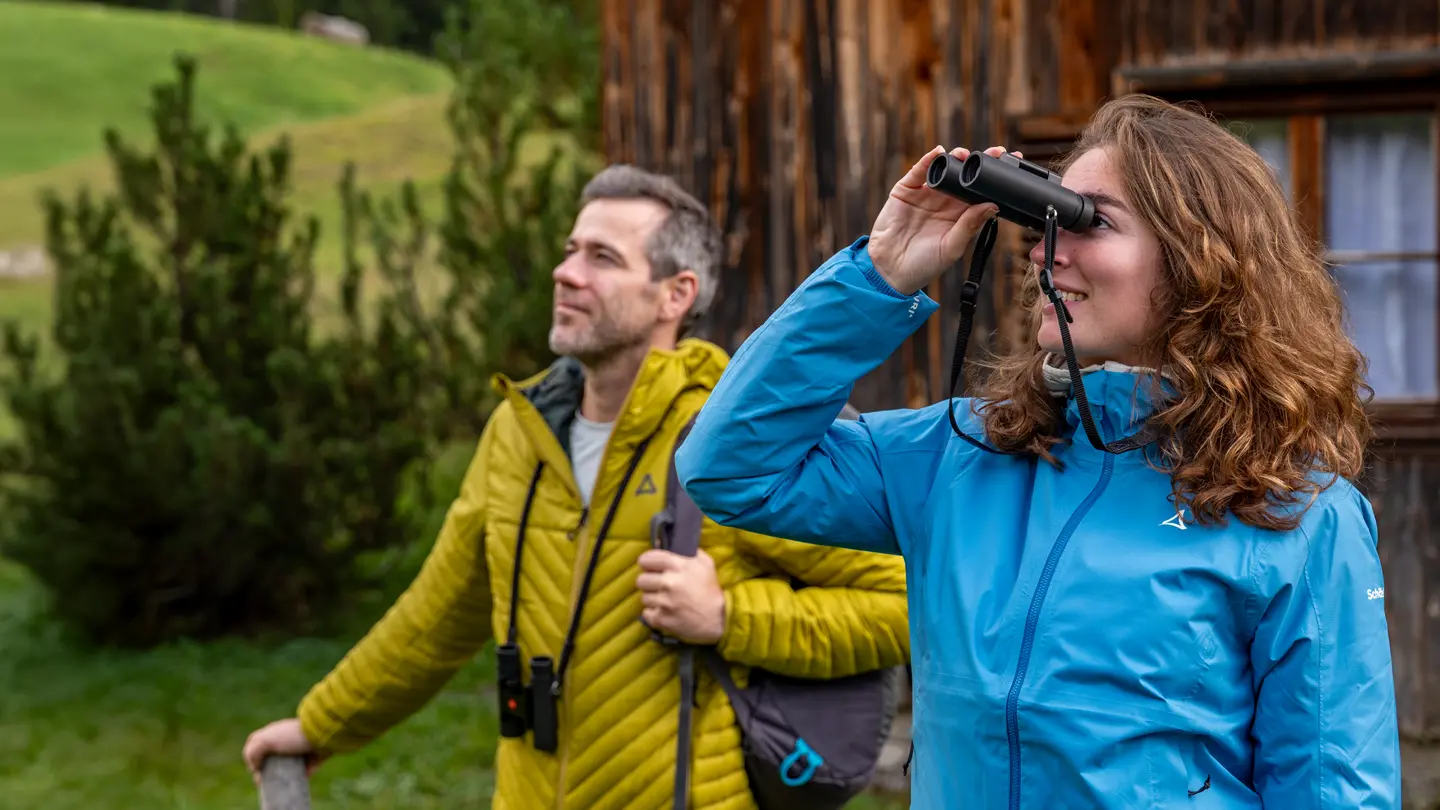 Two hikers are looking through their Leica Noctivid Compact
