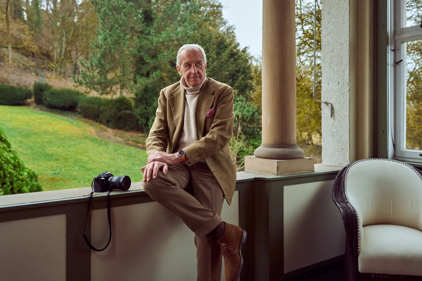 John Golberger is sitting on a veranda with a Leica beside him and a Leica ZM 12 on his wrist