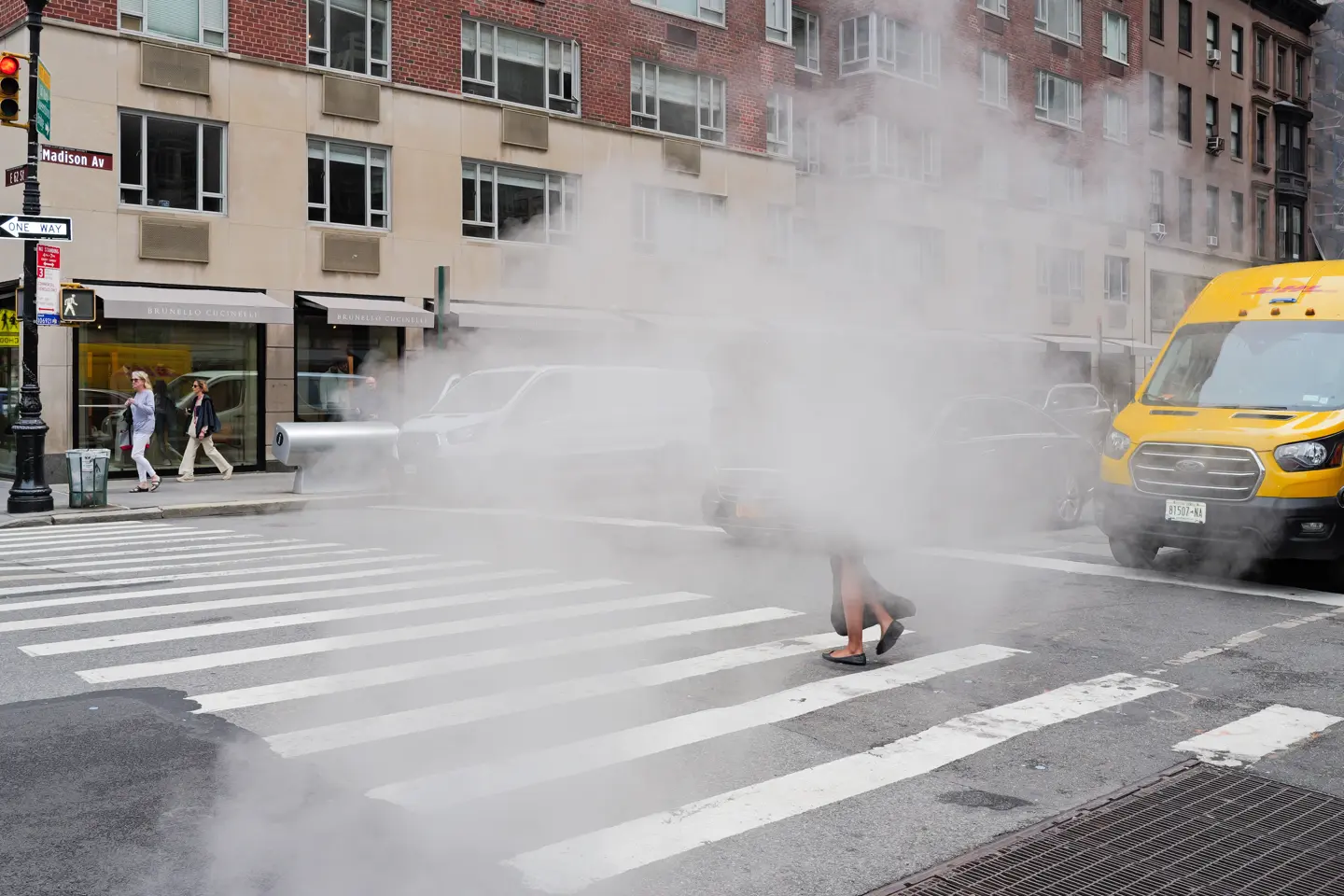 A woman walks along a pavement through the fog