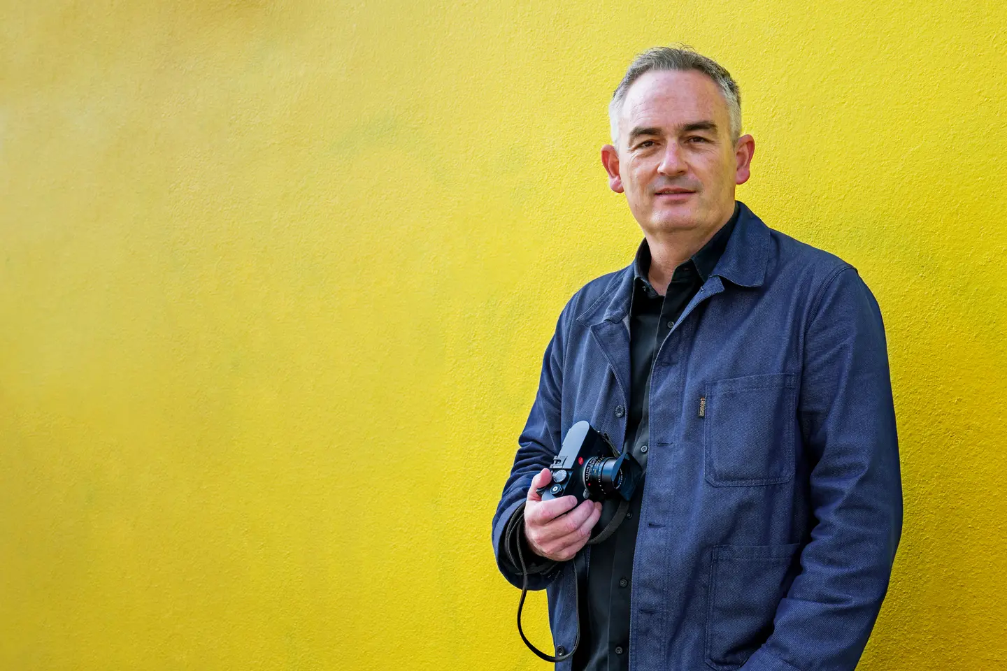 Jesse Marlow with a Leica M EV1 in front of a yellow wall