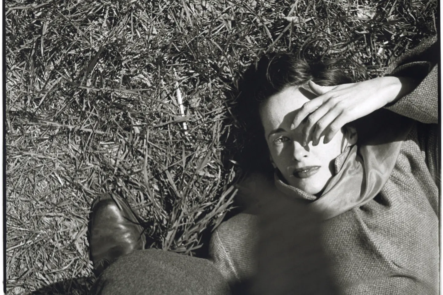 Frau liegt im im Gras und hält sich Hand ins Gesicht, Saul Leiter