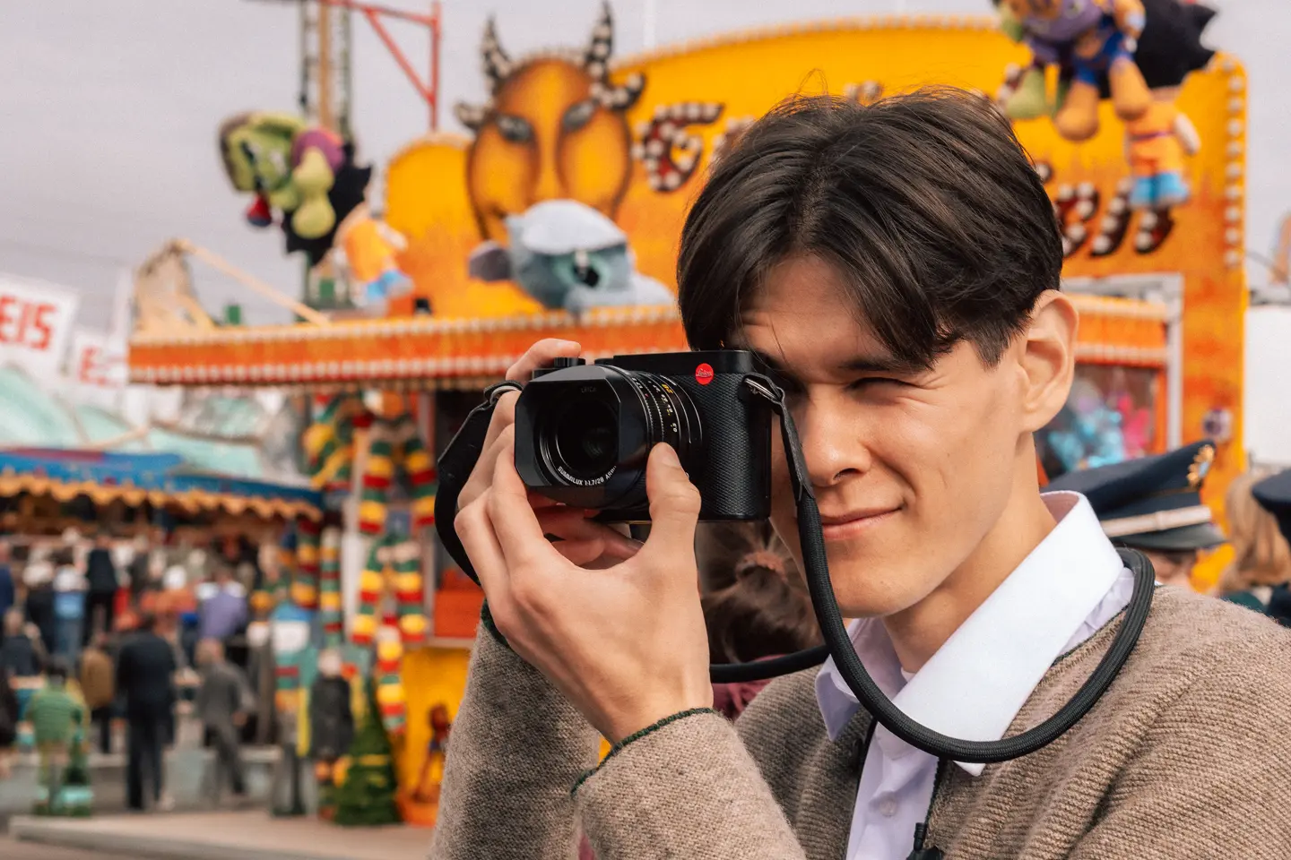 Teo Crawford using a Leica Q3 at Munich Oktoberfest, capturing candid moments in front of a colorful fairground booth during the world's largest folk festival.