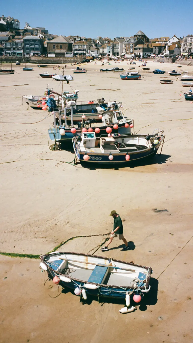 Colour of a British sea side of boats during low tide and a man walking next to one