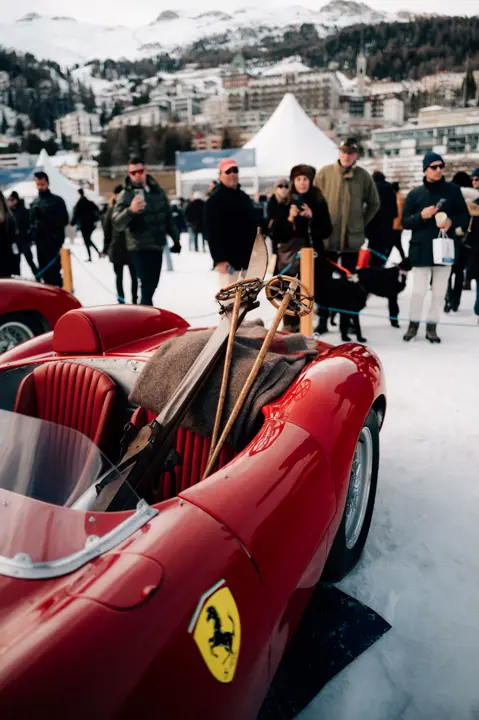 red sports car in a snowy landscape and a lot of people around the car