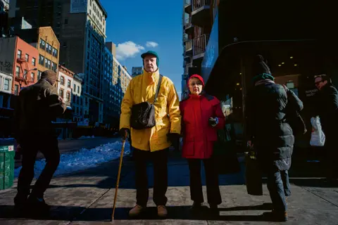 Old couple wearing red and yellow jackets in the streets of New York