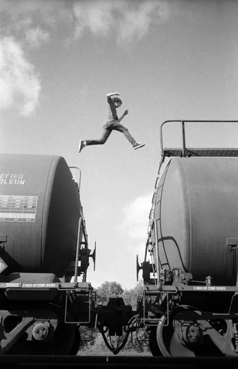 person jumping on a train b&w