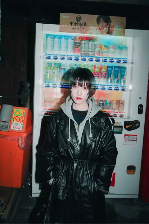 Portrait d'une femme dans la rue devant un distributeur de boissons