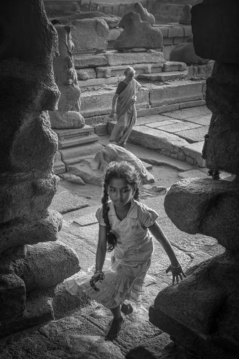 Black-and-white photo of a girl running through a ruin