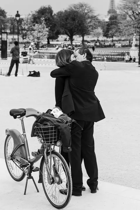 A black-and-white photo of a couple kissing in a park