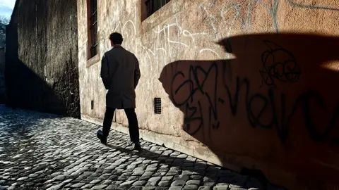 A man walking down a deserted alley in Italy