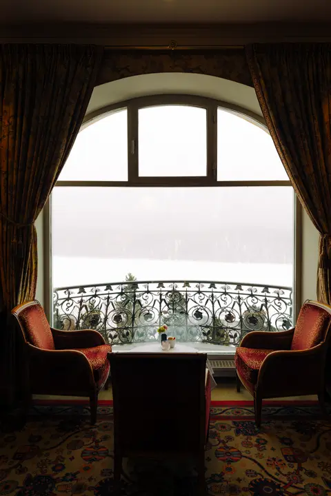 Elegant hotel lounge overlooking a snowy landscape through a large arched window.
