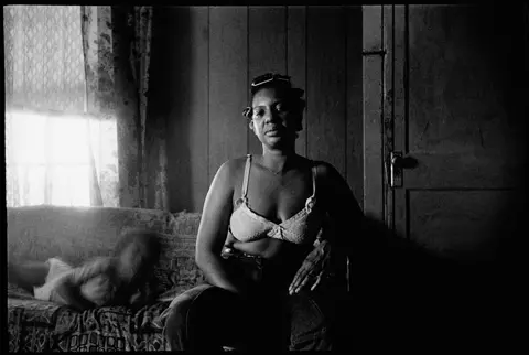 Frances at home with her child in Arkansas. Analog black-and-white photograph from Lisa McCord’s multi-generational project documenting life in the Arkansas Delta.