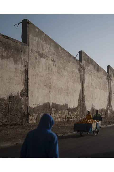 Un homme et son fils dans la rue, poussant un chariot rempli d'agrumes
