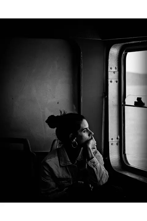 Portrait d'une femme assise dans un train, regardant par la fenêtre