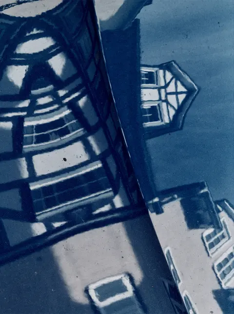 Reflection of historic architecture in a glass surface, creating an abstract composition of urban geometry and architectural detail.