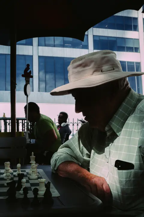 Chess player concentrating over an outdoor game in a public park.