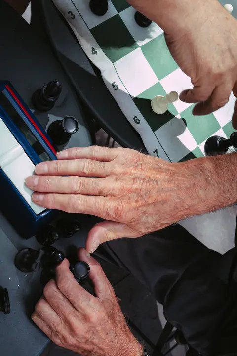 Hands making a move and pressing a chess clock during an outdoor game.