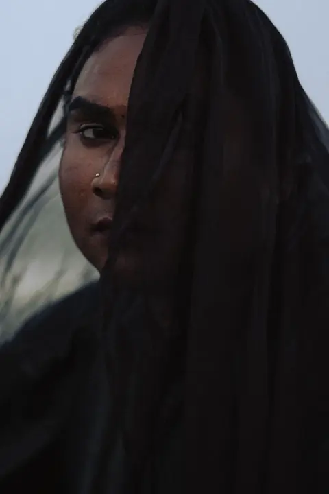 Portrait d'une femme au regard intense, le visage dissimulé par un voile noir